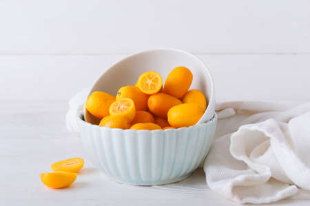 Bowl with tasty kumquat fruits on light wooden backgroundの写真素材
