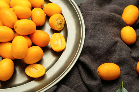 Plate with tasty kumquat fruits on dark backgroundの写真素材