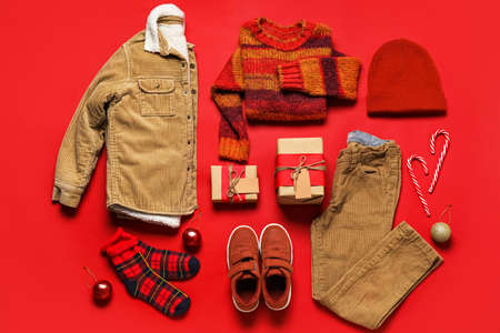 Set of children's clothes with Christmas gifts on color backgroundの写真素材