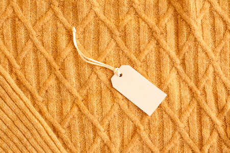 Blank price tag on knitted sweater as backgroundの写真素材