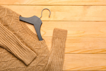Hanger with knitted sweater on wooden background, closeupの写真素材