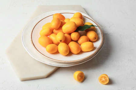 Plate with tasty kumquat fruits on light backgroundの写真素材