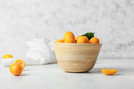 Bowl with tasty kumquat fruits on light backgroundの写真素材