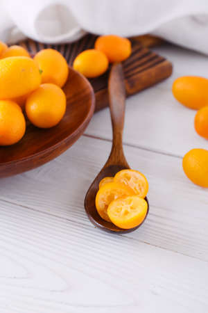 Plate and spoon with tasty kumquat fruits on light backgroundの写真素材