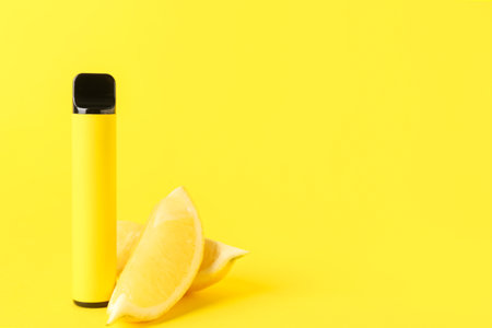 Disposable electronic cigarette and lemon on yellow backgroundの写真素材