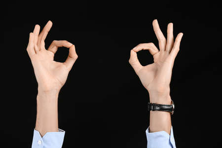 Businessman showing OK on black background