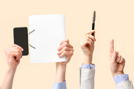 Business people with mobile phone, folder and pen on beige backgroundの写真素材