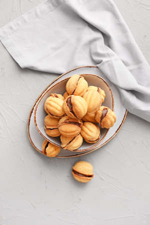 Bowl of tasty walnut shaped cookies with condensed milk on table