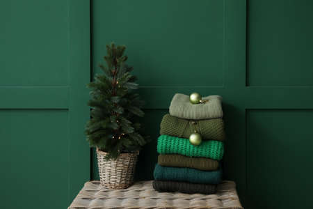 Winter sweaters with Christmas tree on chest near color wall in roomの写真素材