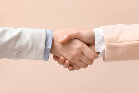 Business colleagues shaking hands on beige background, closeup