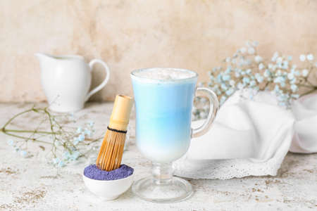 Glass of blue matcha latte, powder and chasen on light backgroundの写真素材