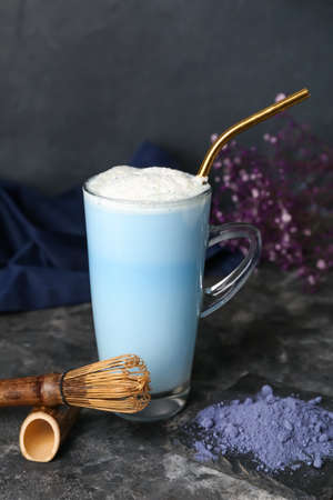 Cup of blue matcha latte, powder and chasen on dark backgroundの写真素材