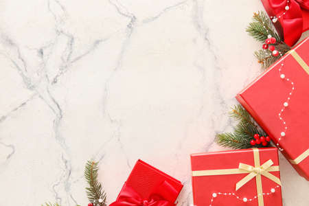 Beautiful composition with Christmas gift boxes and fir branches on white marble backgroundの写真素材