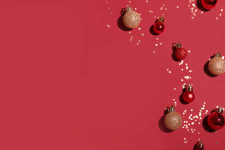 Different bright Christmas balls with confetti on color backgroundの写真素材