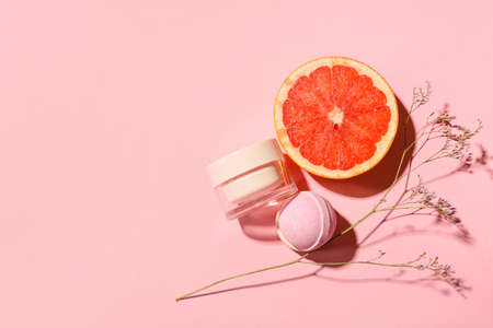 Bath bomb, jar of cosmetic product, grapefruit and dried flower on color backgroundの写真素材