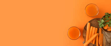 Glasses of fresh carrot juice on orange background with space for textの写真素材