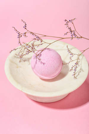 Bowl with bath bomb and dried flower on pink background, closeupの写真素材