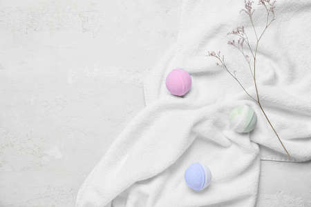 Bath bombs, clean towel and dried flower on light background