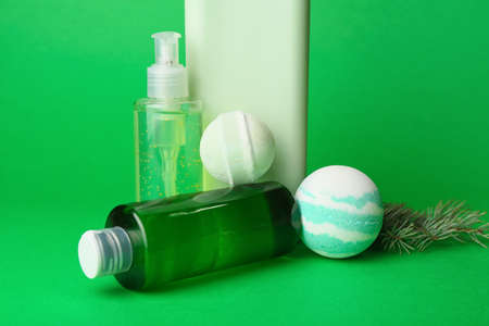 Bottles of cosmetic products, bath bombs and fir branches on green backgroundの写真素材