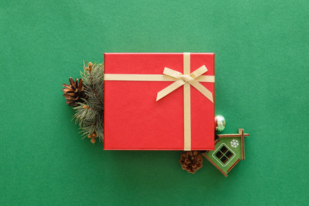 Composition with Christmas gift box, model of house and fir branch on green backgroundの写真素材