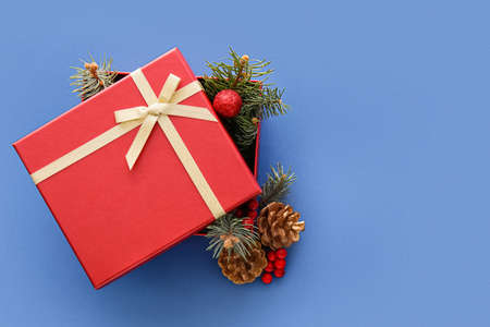 Composition with Christmas gift box, cones and fir branches on blue backgroundの写真素材