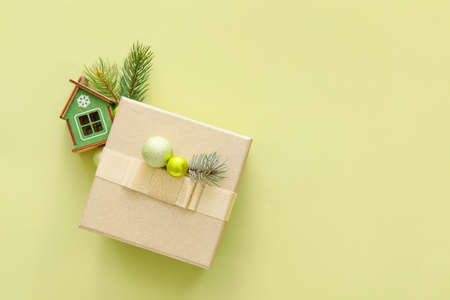 Composition with Christmas gift box, model of house and fir branches on color backgroundの写真素材