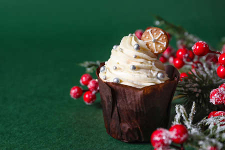 Delicious Christmas cupcakes, fir branch and berries on green backgroundの写真素材