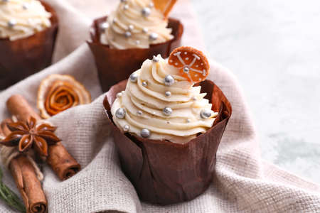 Delicious Christmas cupcakes on light background