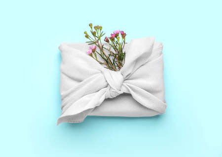 Gift box wrapped in cotton fabric with flowers on blue backgroundの写真素材