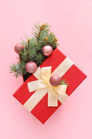 Composition with Christmas gift box, balls and fir branches on pink backgroundの写真素材