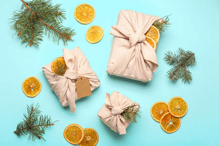 Christmas gifts wrapped in cotton fabric, dried orange slices and fir branches on blue backgroundの写真素材