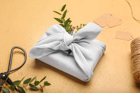 Beautiful gift box wrapped in fabric on color backgroundの写真素材