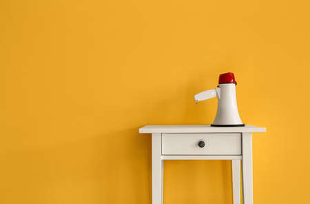 Table with megaphone near yellow wall