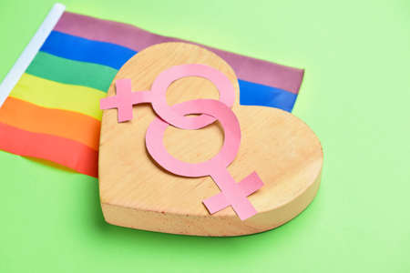 Wooden heart with symbols of woman and rainbow flag on color background. LGBT conceptの写真素材