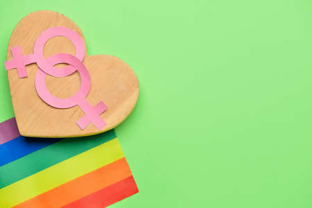 Wooden heart with symbols of woman and rainbow flag on color background. LGBT conceptの写真素材
