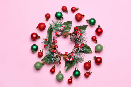 Composition with Christmas wreath and decorations on pink background