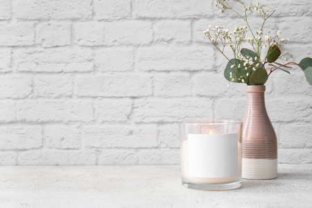 Glass holder with burning candle and flowers on light tableの写真素材