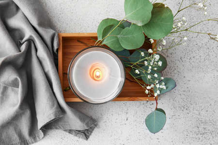 Wooden box with burning candle and flowers on light table, closeupの写真素材