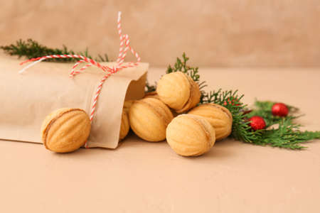 Paper bag with tasty walnut shaped cookies and thuja branches on color background, closeupの写真素材
