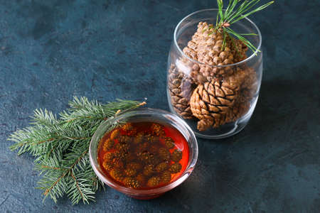 Bowl of tasty pine cone jam and fir tree branch on dark backgroundの写真素材