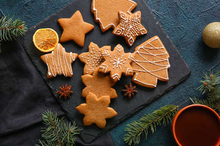 Board with sweet Christmas gingerbread cookies on black background