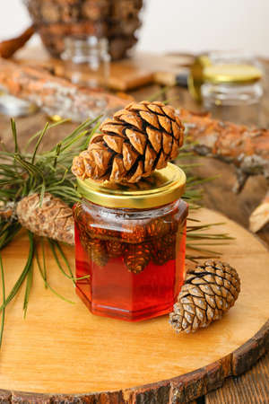 Jar of tasty pine cone jam on wooden table