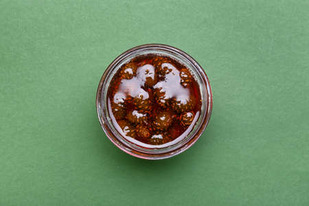 Jar of tasty pine cone jam on green backgroundの写真素材