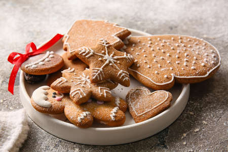Plate with sweet Christmas gingerbread cookies on gray background