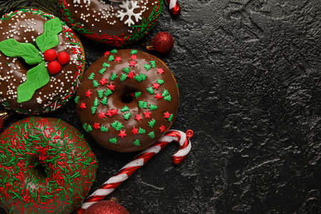 Tasty Christmas donuts with balls and candy cane on dark backgroundの写真素材