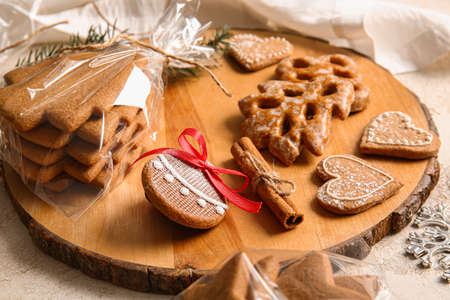 Wooden board with tasty Christmas gingerbread cookies on light backgroundの写真素材