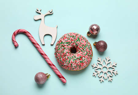 Tasty Christmas donut with figures, balls and candy cane on blue backgroundの写真素材