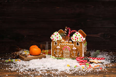 Beautiful gingerbread house, tangerines and snow on wooden backgroundの写真素材