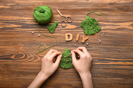 Woman making handmade Christmas toys and word DIY on wooden backgroundの写真素材