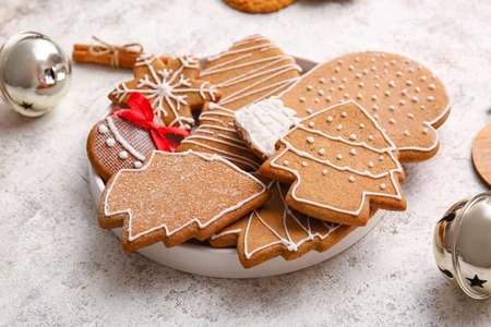 Plate with delicious gingerbread cookies on light background